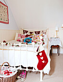 Christmas stocking hangs on metal footboard of bed