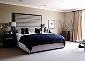 Dark blue covers on bed with side tables and matching lamps