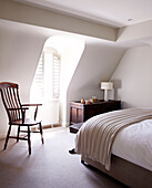 Wooden chair at dormer window in cream bedroom