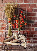 Dried flowers and metal chair against brick wall in Essex England UK