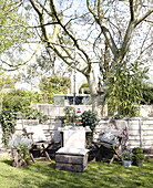 Tisch und Stühle unter einem Baum neben einem Zaun im Garten der Stadt Bath Somerset, England, UK