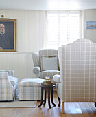 Checked armchairs and louvered window in living room of Hampshire home England UK