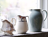 Drei Milchkännchen auf der Fensterbank eines Landhauses in Hexham, Northumberland, England, UK