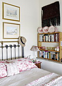 Floral pillows and brass headboard with bookcase in Hexham country bedroom Northumberland England UK