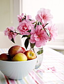 Schale mit Äpfeln und rosa Blumen in einem Haus in Harrogate, Yorkshire, England, UK