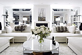 Weiße Sofas und runder Couchtisch im verspiegelten Wohnzimmer eines Londoner Hauses UK