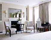 Dark wood chairs at fireplace in classic master bedroom of London home, England, UK