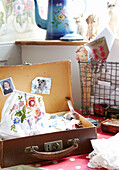 Embroidered fabric and photographs in vintage suitcase in Oxfordshire home, England, UK