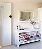 Folded cushions and blankets on console in bedroom of Oxfordshire cottage, England, UK