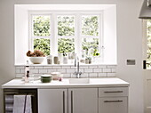 Ceramic kitchenware on sunlit windowsill with sink in contemporary Oxfordshire cottage, England, UK