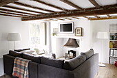 Graues Sofa im Wohnzimmer mit Balken in einem modernen Landhaus in Oxfordshire, England, UK