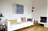 Kunstwerk auf Leinwand über weißem Sofa am Kamin im Wohnzimmer eines Hauses in Bussum, Niederlande
