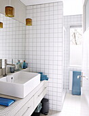 White tiled bathroom with coloured glass pendants and large mirror above sink in Bussum home, Netherlands