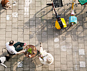 Menschen sitzen mit ihrem Hund in einem Straßencafé, während eine Frau auf der Straße zeichnet, Amsterdam, Niederlande