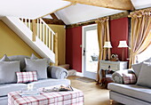 Hellblaue Sofas mit karierten Kissen in einem gelb-roten Wohnzimmer, Oxfordshire, England, UK