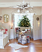 Daybed and logs with Christmas tree in living room of Derbyshire farmhouse England UK