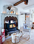 Rocking chair with lit wood burning stove in living room of Derbyshire farmhouse England UK