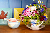 Cut flowers in teacup with bowl and tiles in Surrey farmhouse England UK