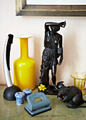 Yellow vase with black figurine and hole punch in London townhouse England UK