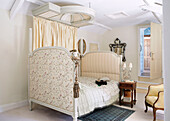 Upholstered antique bed in cream bedroom of traditional country house Welsh borders UK