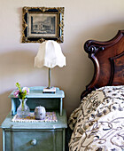 Vintage artwork with polished wooden headboard bedroom detail in traditional country house Welsh borders UK