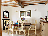 Dining table with painted chairs in beamed rural Oxfordshire cottage England UK