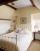Quilted bed at window of beamed Bicester farmhouse Oxfordshire England