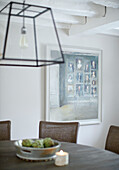Framed artwork with large glass pendant shade over dining table in Buckinghamshire home UK