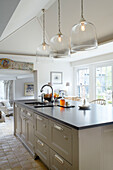 Double sink in kitchen island below glass pendant shades in Buckinghamshire kitchen UK