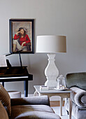 Cremelampe auf Beistelltisch mit Klavier und gerahmtem Porträt in einem Haus in Buckinghamshire, UK