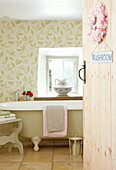 Freistehende Badewanne unter dem Fenster mit Blattmotivtapete in einem Cottage in Devonshire UK