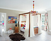 brown rug and colourful chandelier with four postered bed in Northumbrian manor house England UK