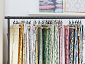 Assorted fabrics hang on clothes rail in Northumbrian textiles studio England UK