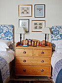 Framed artwork above Russian dolls on wooden chest of drawers with blue floral twin headboards in Hexham home Northumberland UK