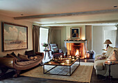 Tealights and pinecones on table with antique sofa and lit fire in Oxfordshire home