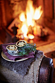 Mince pies and pine needles on folded blankets at lit fire in Oxfordshire home England UK