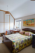 Polished dark wooden bed with yellow embroidered bedspread in Speldhurst home Kent England UK