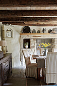 Dining chairs at table with carved wooden sideboard and exposed stone fireplace in Grade II listed Tudor bastle Northumberland UK