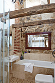 Mirror above bath in exposed stone and brick Grade II listed Tudor bastle Northumberland UK