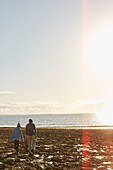 Man and boy walk across rocks towards sea in County Sligo in Connacht, Ireland