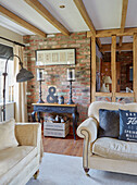 Vintage lamp and upcycled side table in exposed brick living room with timber frame in County Durham cottage, England, UK
