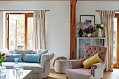 Rosa geknöpfter Sessel mit Sofa und offener Gartentür in einem Haus in Kent, England, UK