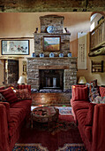 Pair of striped red sofas with exposed stone fireplace in Herefordshire farmhouse, UK