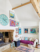 Große Uhr über dem Holzofen mit moderner Kunst in einem Bauernhaus in Warwickshire, UK