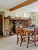 Elephant statues on wooden dining table with exposed stone fireplace in Oxfordshire cottage, UK