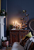 Coal bucket and carved wooden sideboard with lit candles and vintage lamp in East Grinstead home, West Sussex, UK