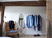 Clothes rail and shoes with armchair and mirror in Warwickshire farmhouse, England, UK