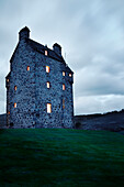 Lit windows in remote Scottish castle, UK