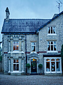 Kiesauffahrt und beleuchtete Fenster einer dreistöckigen Doppelhaushälfte, UK