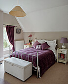 Lila Decke und passende Vorhänge mit Metallrahmenbett in einem britischen Haus